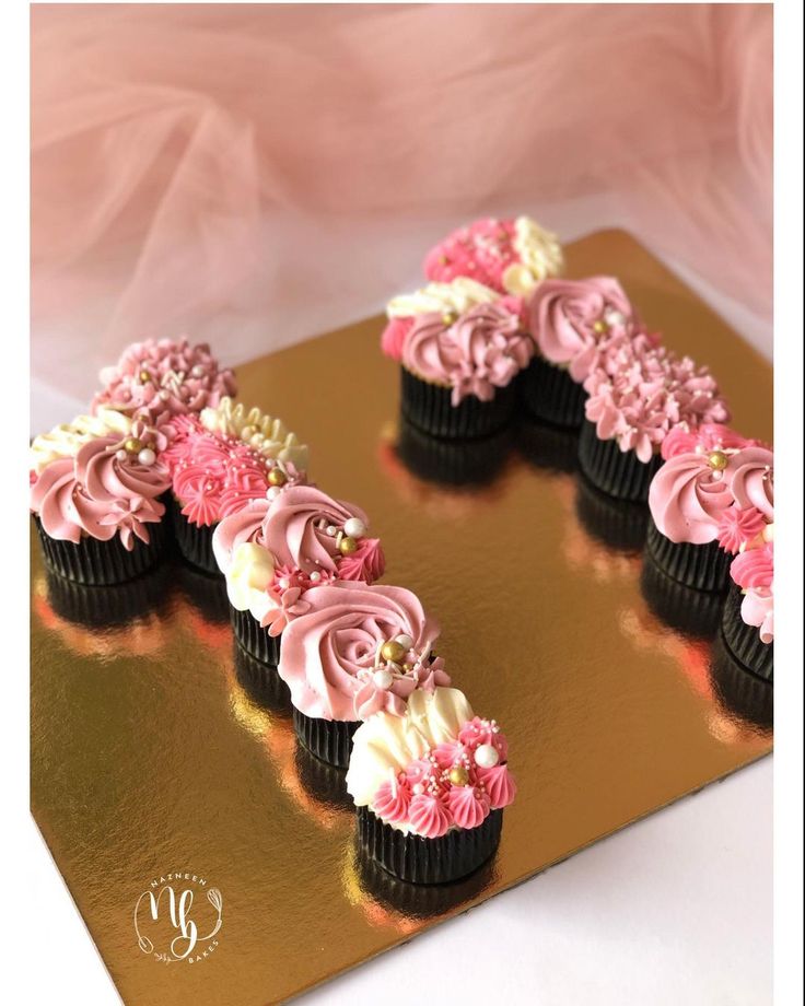 cupcakes with pink and white frosting are arranged in the shape of v