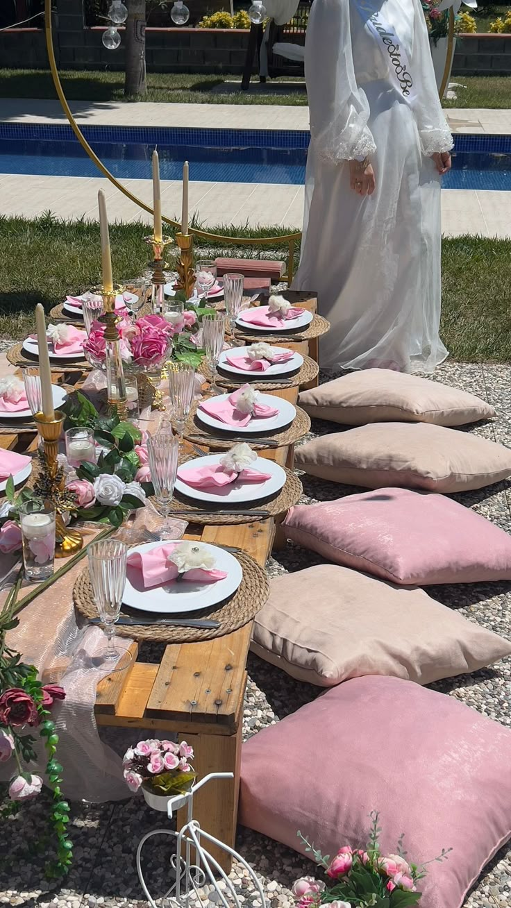 a table set up with pink and white plates, napkins and flowers on it