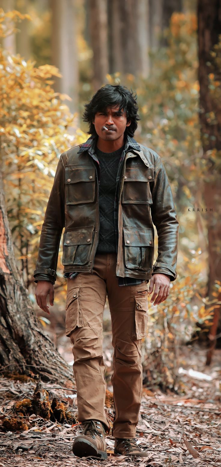 a man walking in the woods wearing a leather jacket