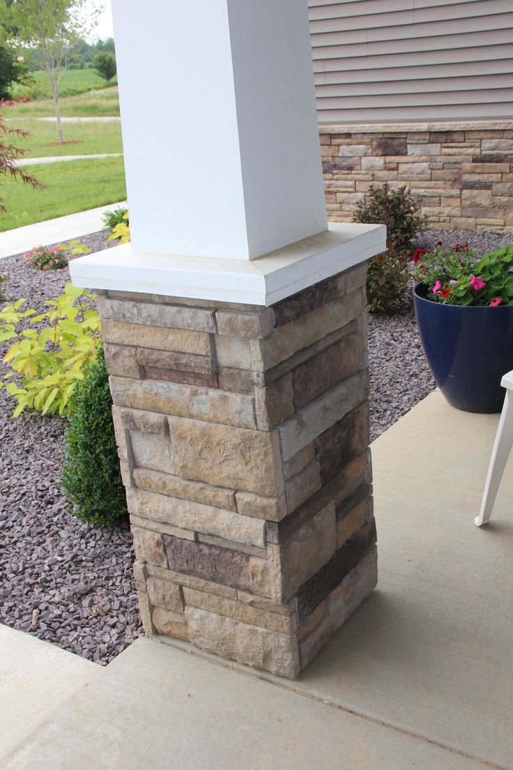 a white chair sitting on top of a patio next to a stone wall and planter