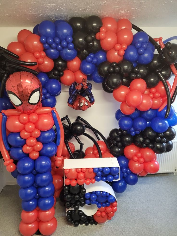 spiderman balloon decorations are displayed on the wall in front of a doorway with balloons