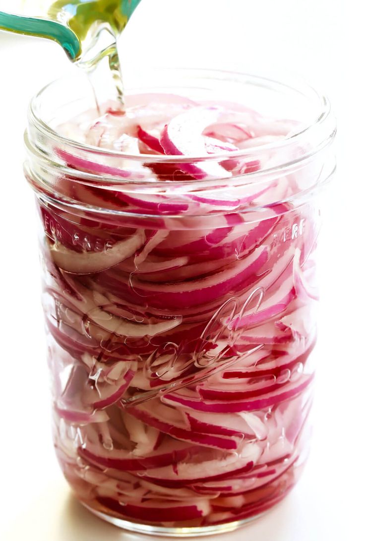 a jar filled with sliced red onions on top of a table