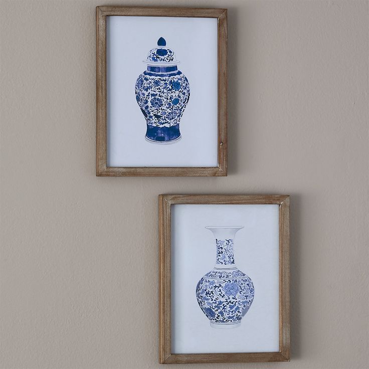 two blue and white vases are mounted on the wall next to each other in wooden frames