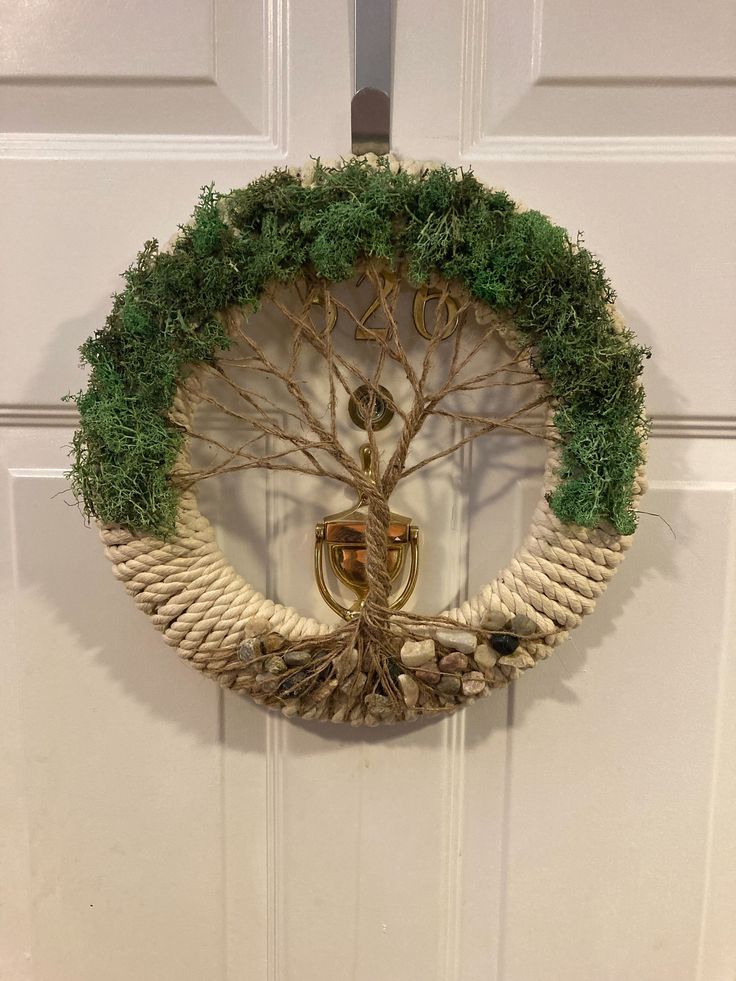 a wreath with a tree on it hanging from the front door