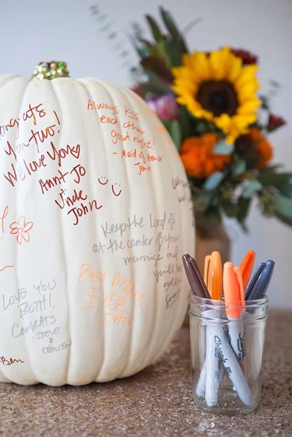 a white pumpkin sitting on top of a counter next to some markers and pencils