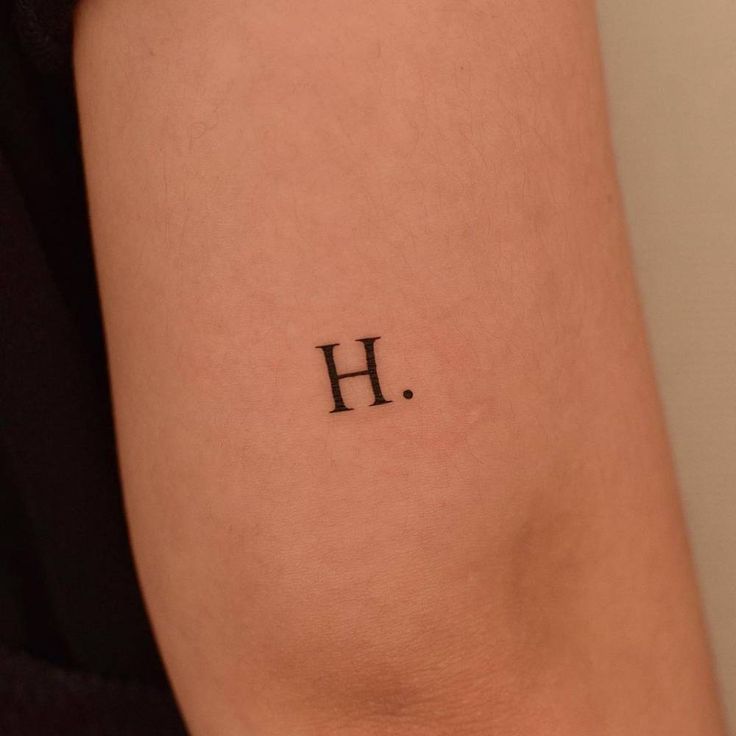 a person with a tattoo on their arm that has the letter h in black ink