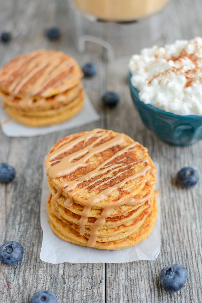 blueberry pancakes with whipped cream on top and two bowls of berries in the background