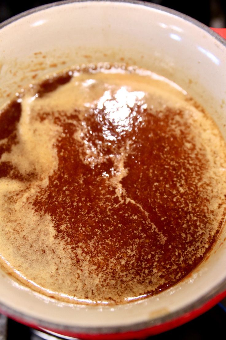 a bowl filled with brown liquid sitting on top of a stove