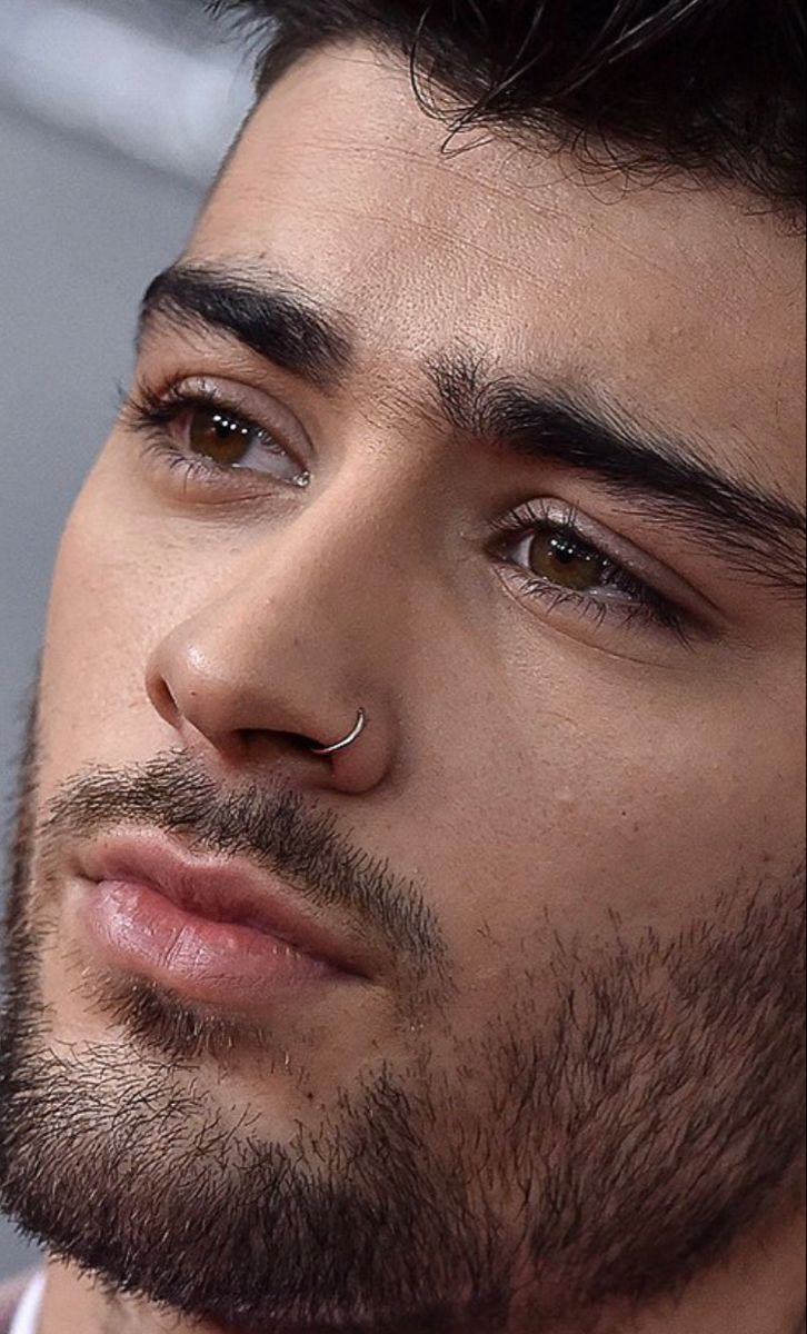 a close up of a person wearing a tie and nose piercings on his face