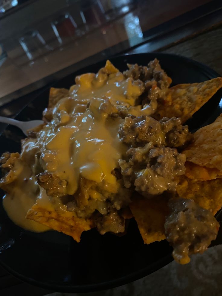 a black plate topped with nachos covered in cheese