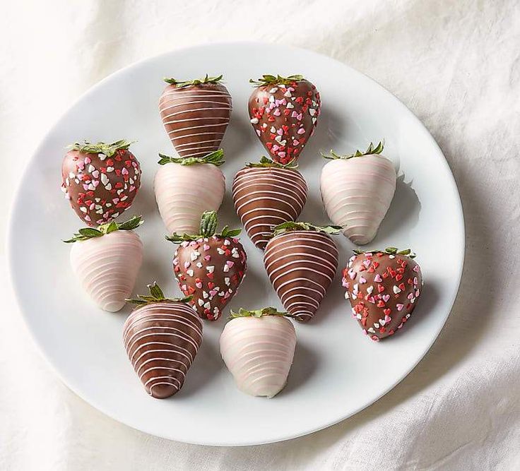 chocolate covered strawberries arranged on a white plate with sprinkles and leaves