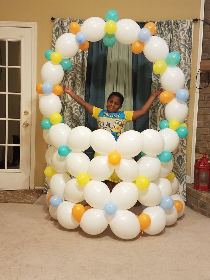 a young boy standing in front of a balloon arch with balloons on the top and bottom