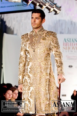 a man is walking down the runway in a gold suit