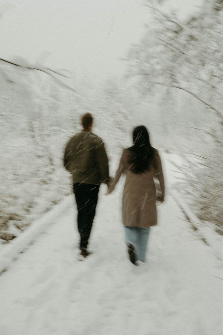 two people walking in the snow holding hands