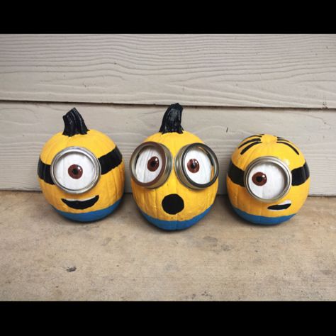 three minion pumpkins with googly eyes are sitting in front of a door