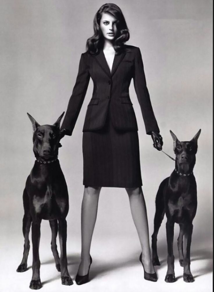 a woman standing next to two dogs on a white background