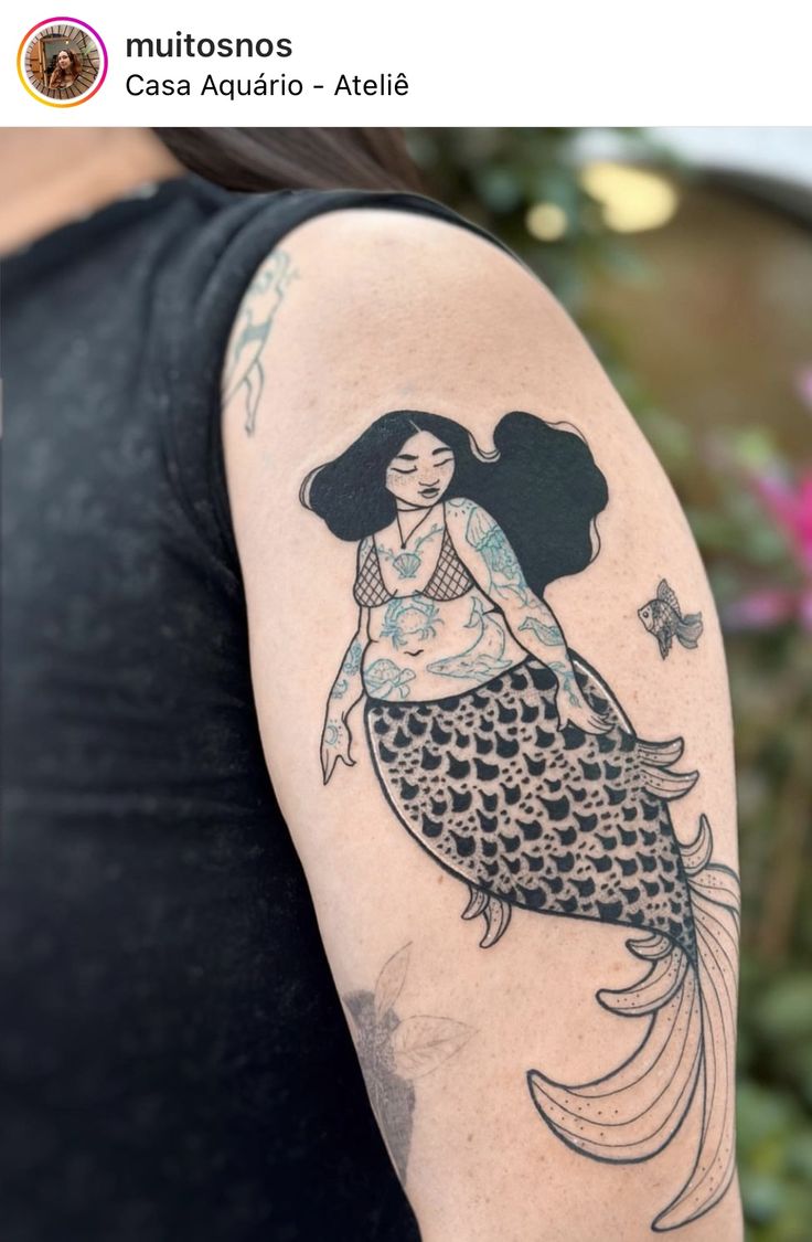 a woman's arm with a tattoo on it and a mermaid sitting on top of her