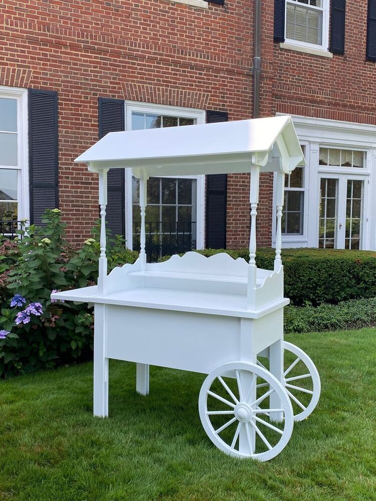 a white cart sitting on top of a lush green field next to a tall brick building