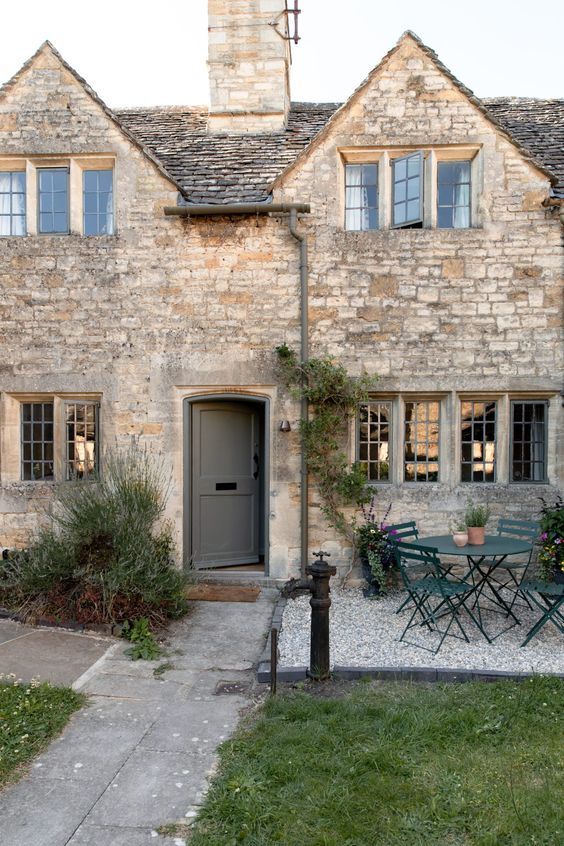 an old stone house with tables and chairs outside