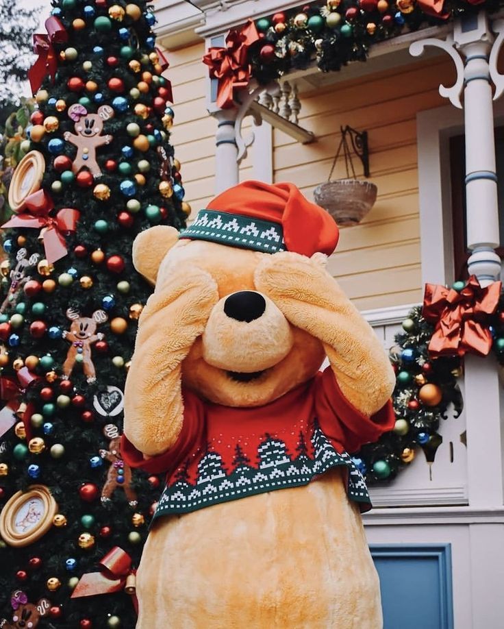 a large teddy bear standing in front of a christmas tree