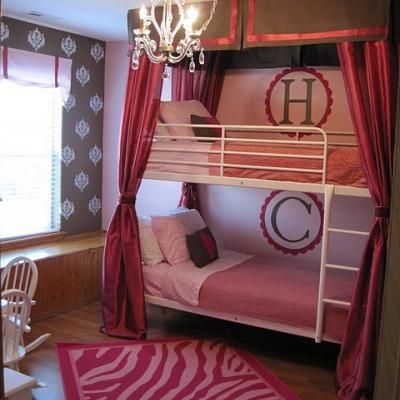 a bedroom with bunk beds and pink rugs on the floor, chandelier hanging from the ceiling