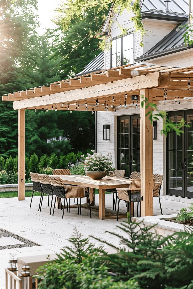 an outdoor dining table and chairs under a pergolated patio with trees in the background