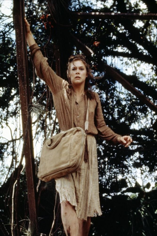 a woman standing on top of a wooden pole holding a bag in her hand and looking up at the sky