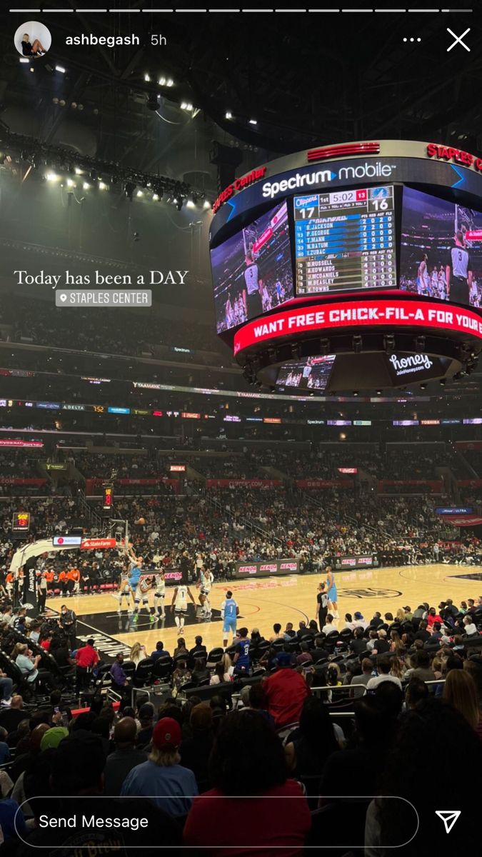 a basketball game is being played on the big screen in an arena with people watching