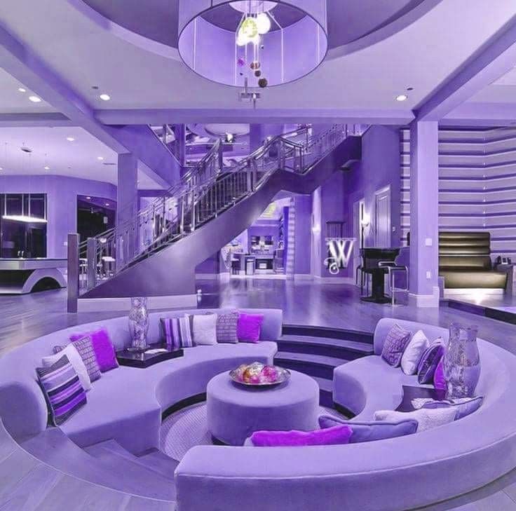 a living room filled with purple couches next to a spiral stair case and table