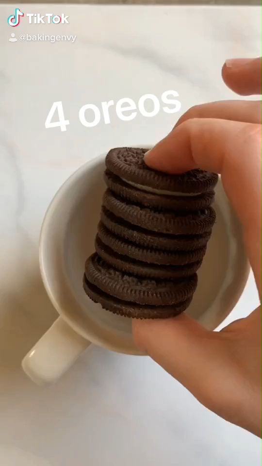 a hand holding a stack of chocolate cookies in a white cup with the words 4 oreos above it