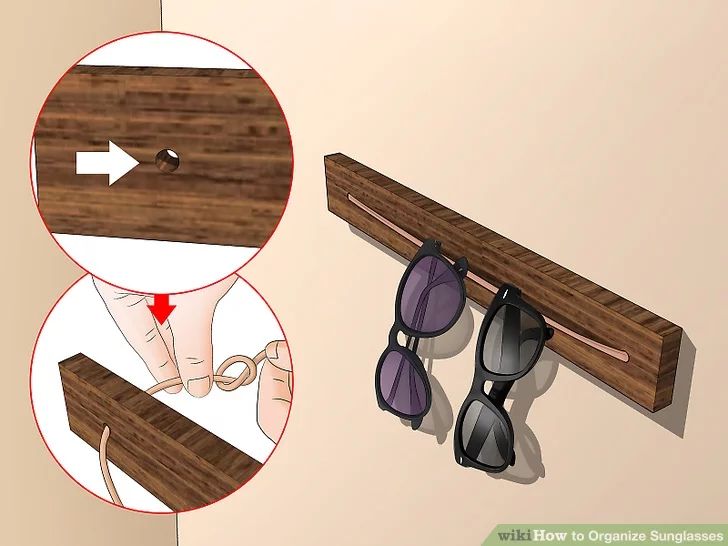 a pair of sunglasses hanging on a wooden shelf next to another pair of sunglasses and a hand holding the rail