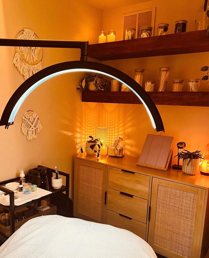 a bed room with a neatly made bed next to a shelf filled with candles and other items