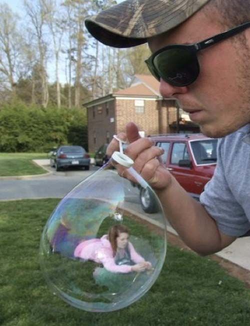 a man is holding a bubble with a girl in it