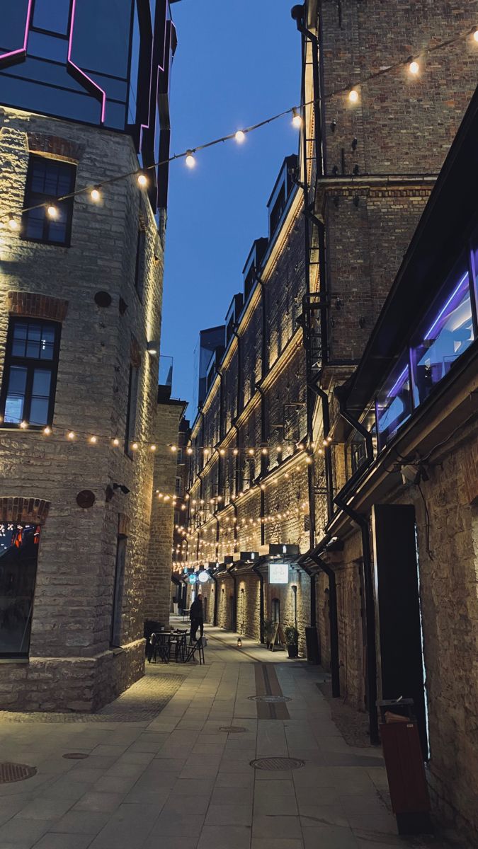 an alley way with lights strung from the buildings