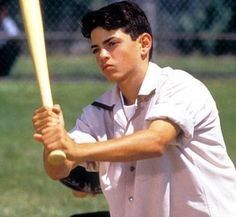 a young man holding a baseball bat on top of a field