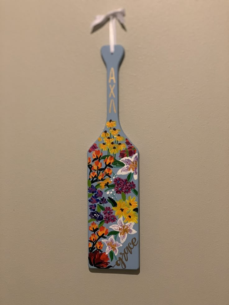 a flowered bottle hanging from the side of a wall with an arrow on it