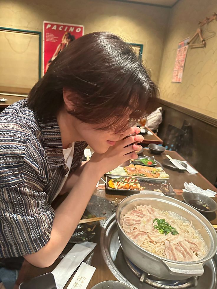 a woman sitting at a table covered in food