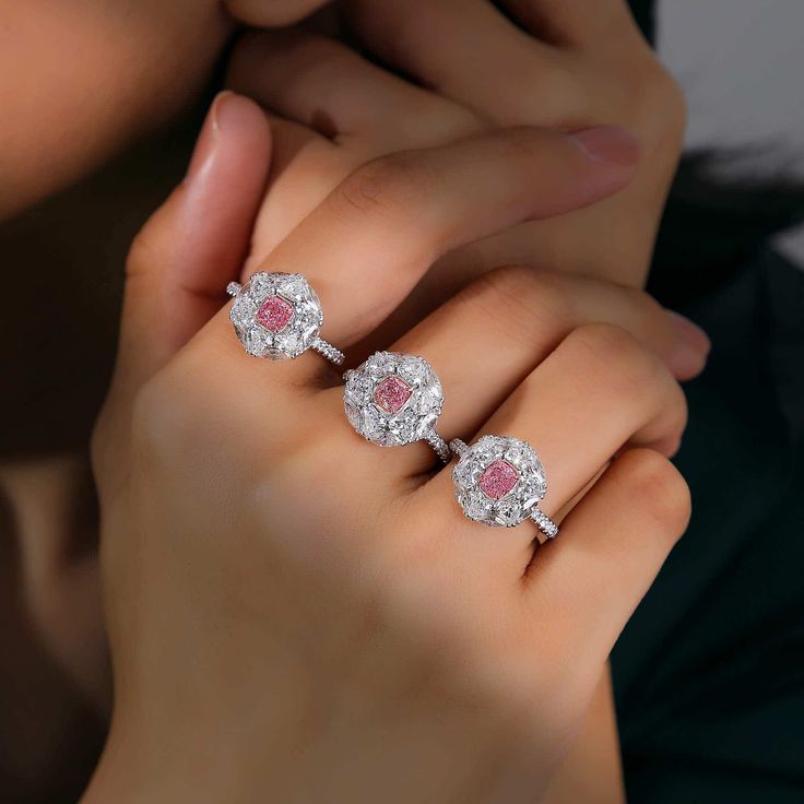 a woman's hand with three diamond and pink sapphire rings on her fingers,