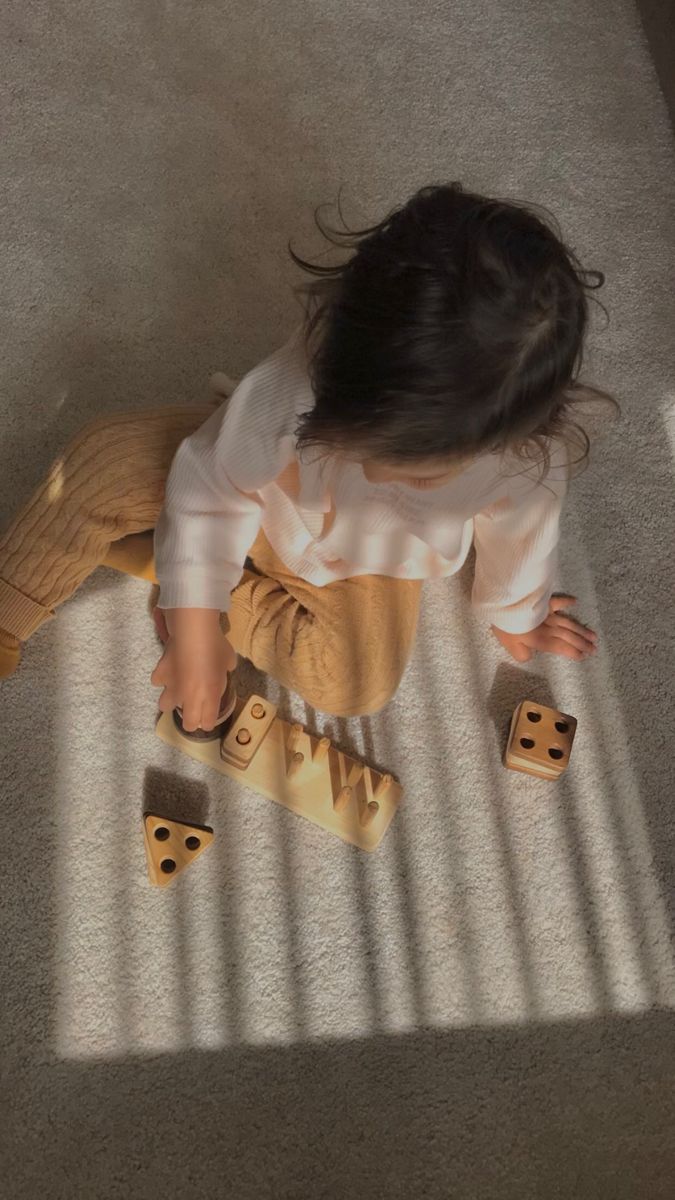 a toddler playing with wooden blocks on the floor