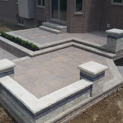 a brick patio with steps and planters in the middle, surrounded by concrete blocks