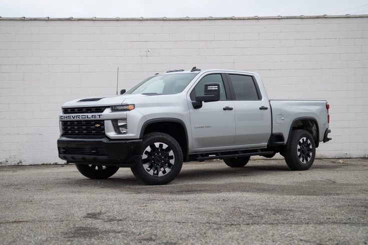 a silver truck parked in front of a white brick wall