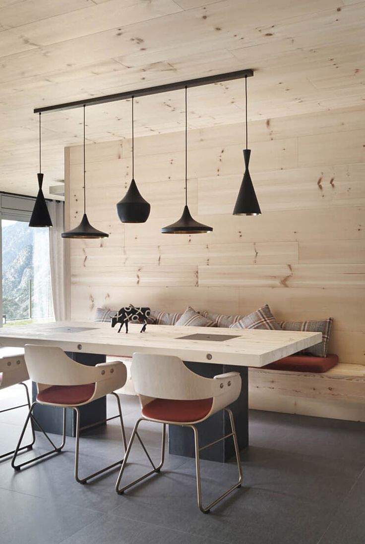 a dining table with four chairs in front of it and some lights hanging from the ceiling