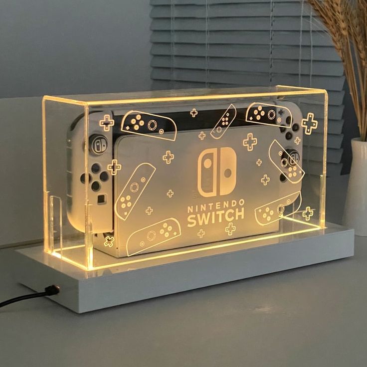 an illuminated nintendo wii game console sitting on top of a table next to a plant