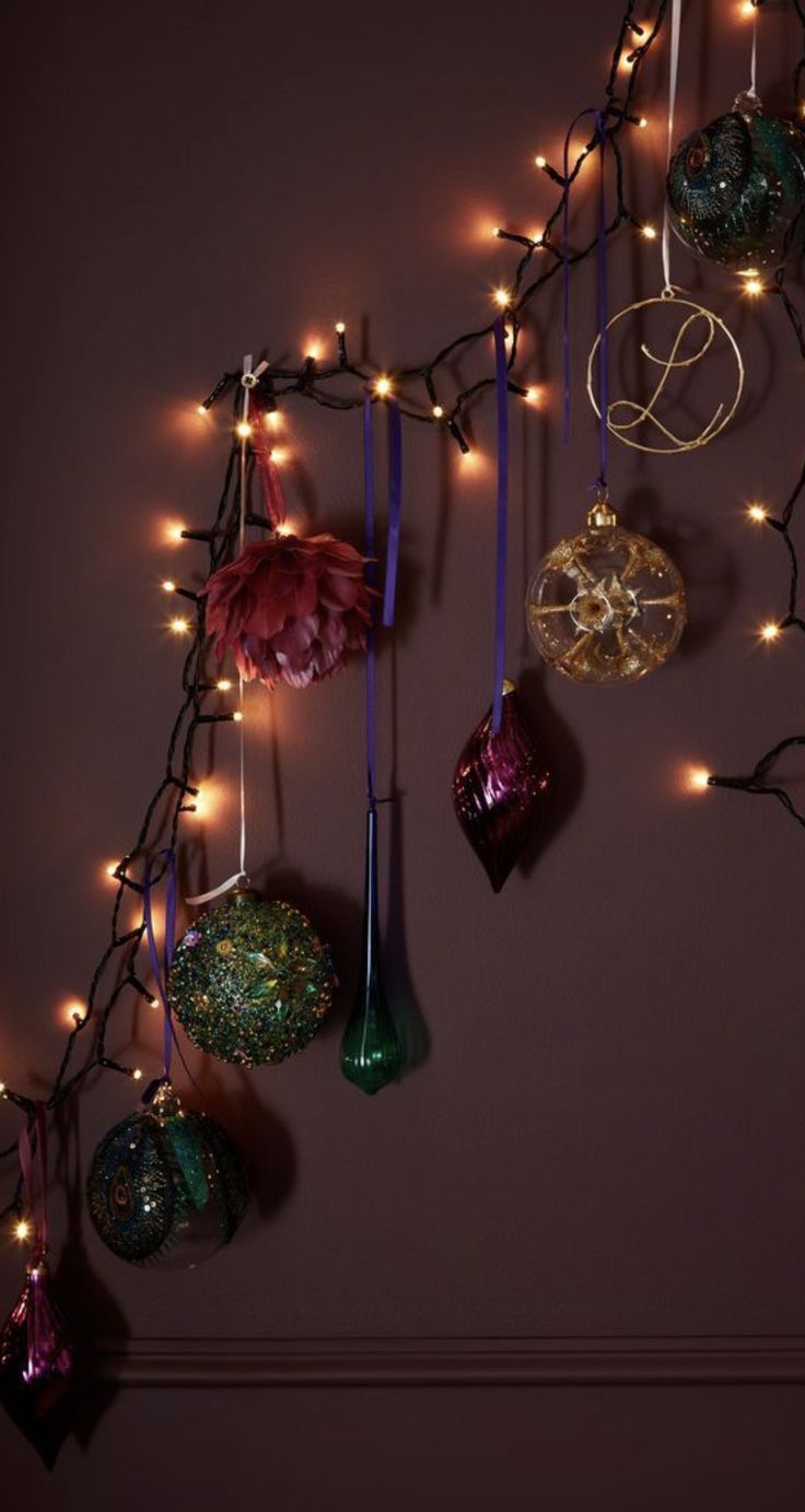 christmas ornaments are hanging on the wall with fairy lights around them, and there is no image here to provide a caption for