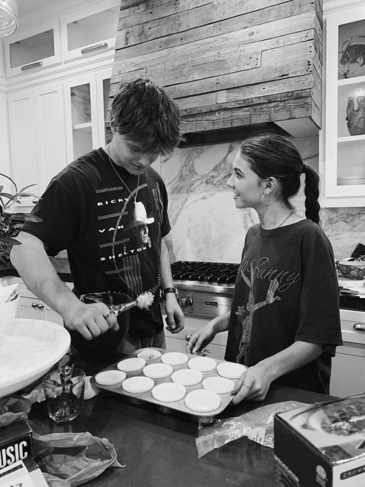 two people in the kitchen making cupcakes