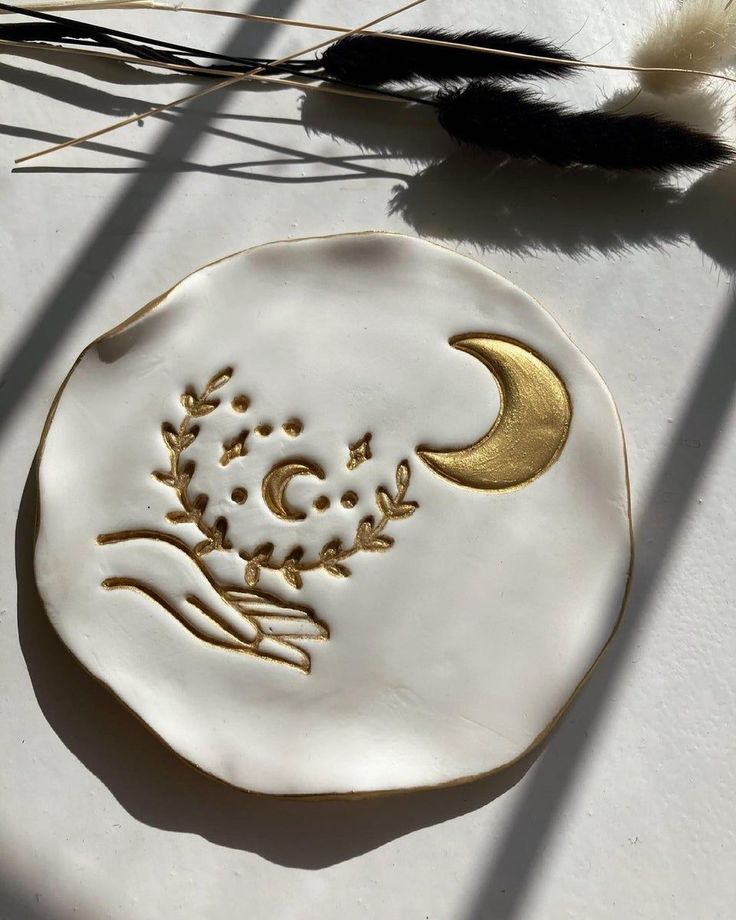 a white and gold plate sitting on top of a table next to feather quills