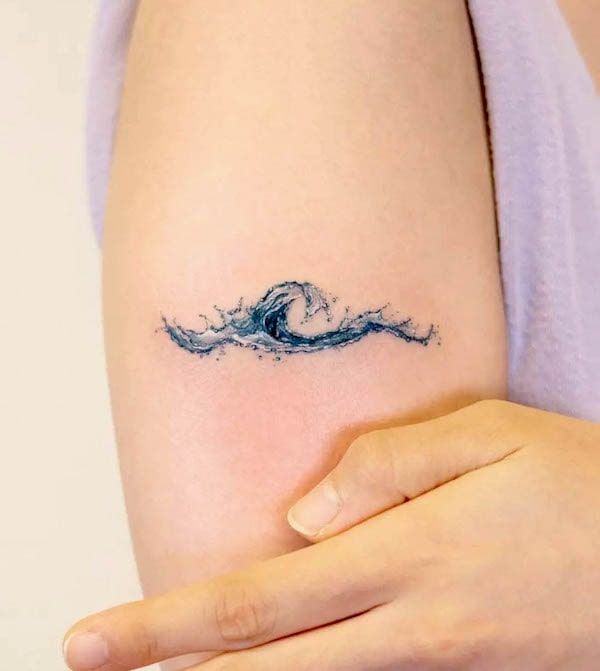 a woman's arm with a wave tattoo on it