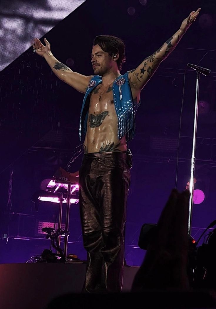 a shirtless man on stage with his arms in the air