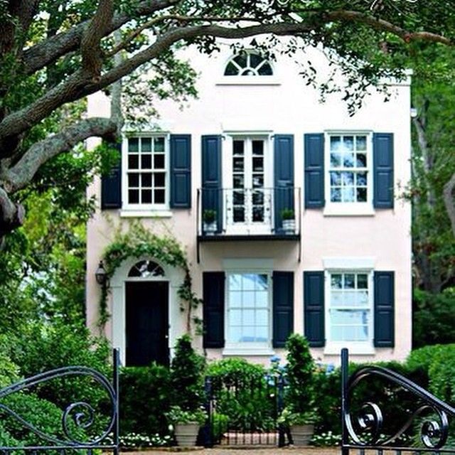 a white house with black shutters and green trees