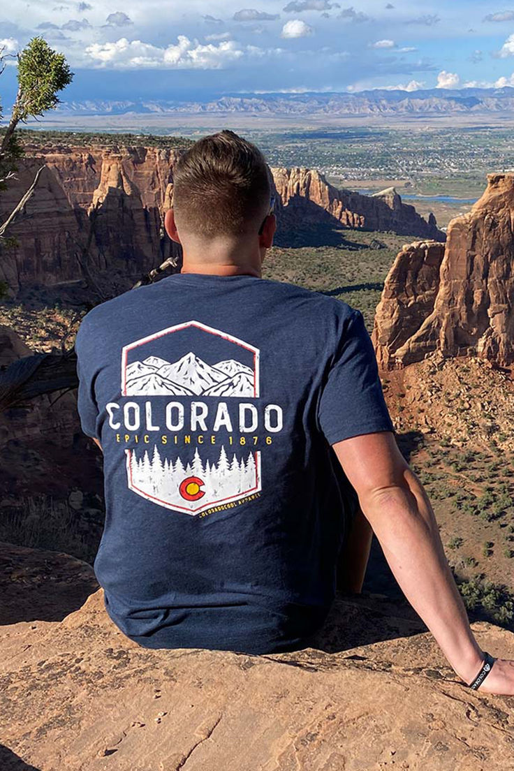 a man sitting on top of a mountain looking at the mountains